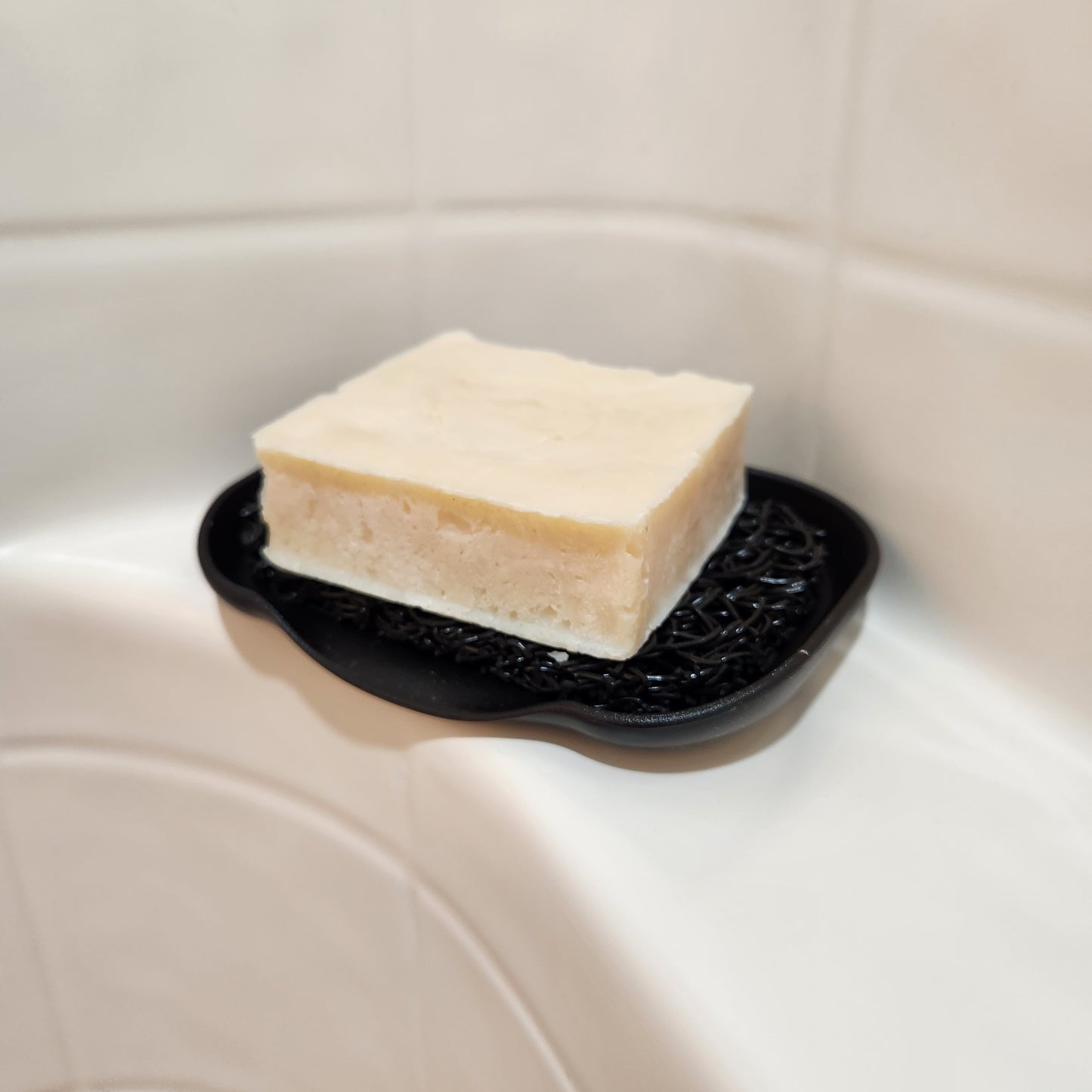 Beard bar soap on a black soap lift and waterfall dish in a shower