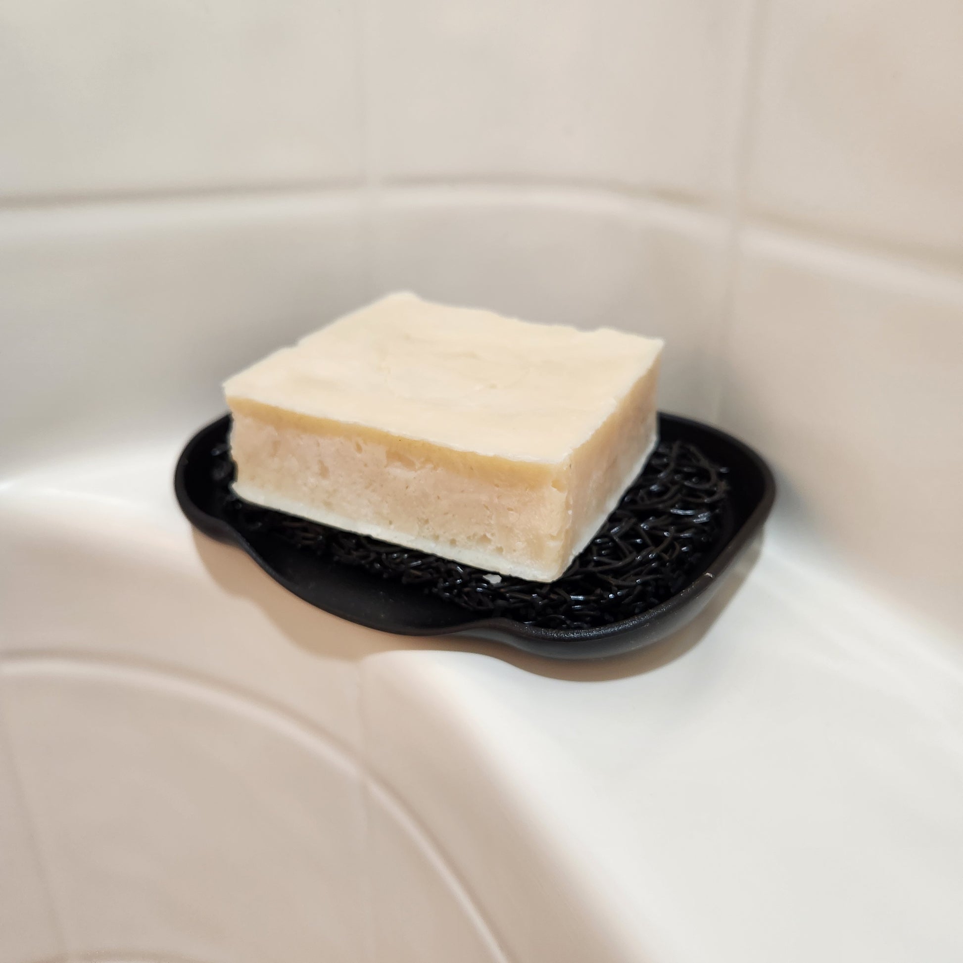 Beard bar soap on a black soap lift and waterfall dish in a shower